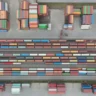 Widok z góry na terminal przeładunkowy: rzędy kontenerów na wagonach i składowisko obok